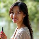 A portrait of a smiling woman, Sophia Chen, an artist, holding an elegant calligraphy pen.